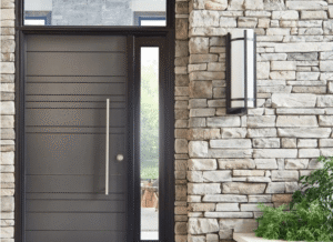 Modern front door with horizontal lines and a tall handle set in a stone wall, next to a glass panel and a wall-mounted outdoor light fixture, complementing homes with luxury pools or custom spas.