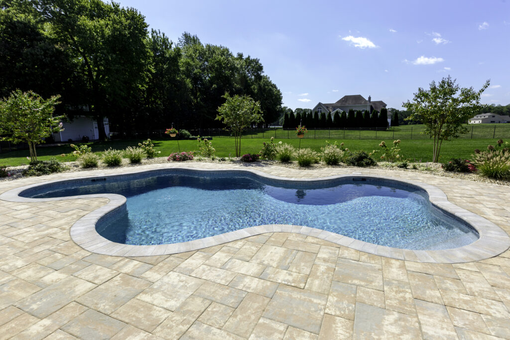 Freeform concrete swimming pool with Nicolock paver patio