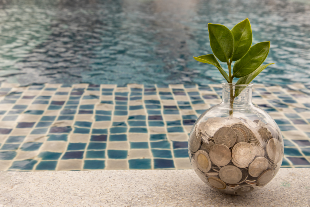 The saplings that grow on the pile of coins In a glass bottle on pool background.