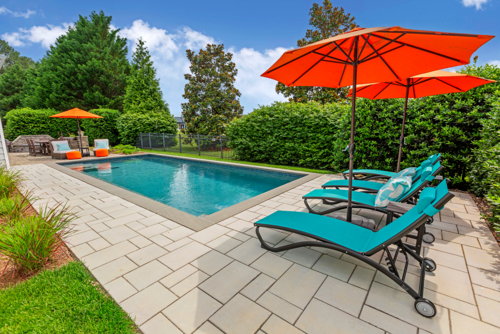 Custom Concrete Pool, with pavers, aqua blue lounge chairs and orange umbrellas