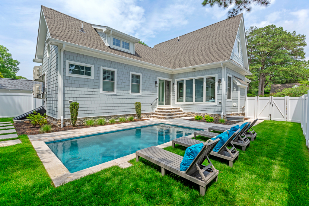 Photo of a backyard with a custom concrete pool with lounge chairs around. Yard repair Assurance Guarantee