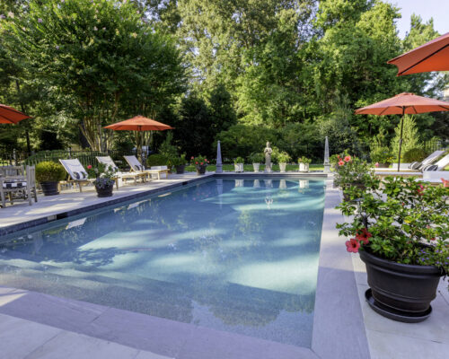 Classic concrete pool with full steps and porcelain paver patio