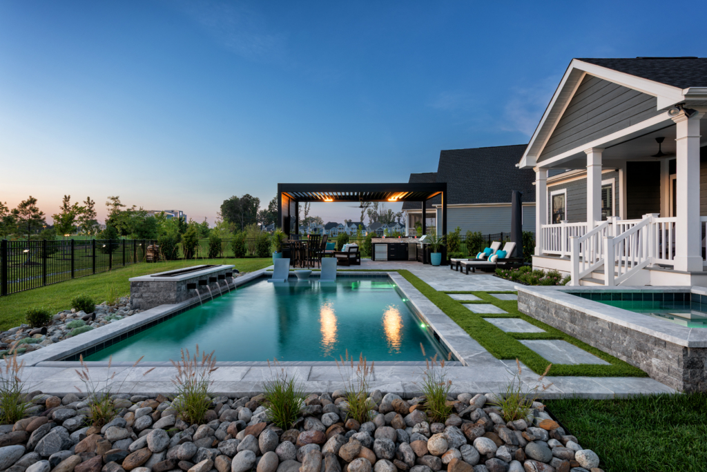 Luxury evening pool with LED lighting, in-water loungers, and outdoor seating | Ashton Pools by Design